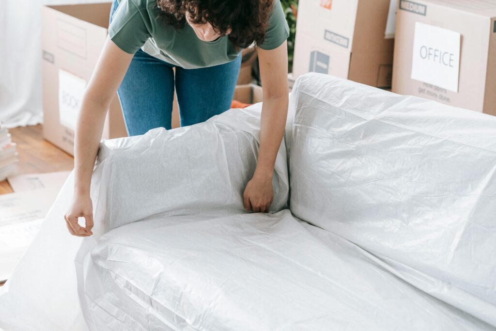 A woman wrapping furniture - a sofa - ready for collection